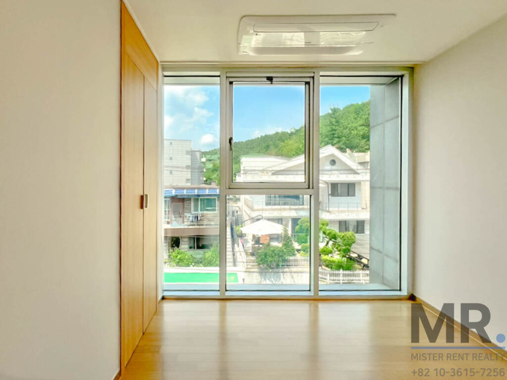 Bedroom with full-height window overlooking a green hillside