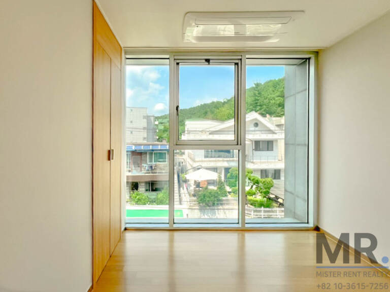 Bedroom with full-height window overlooking a green hillside