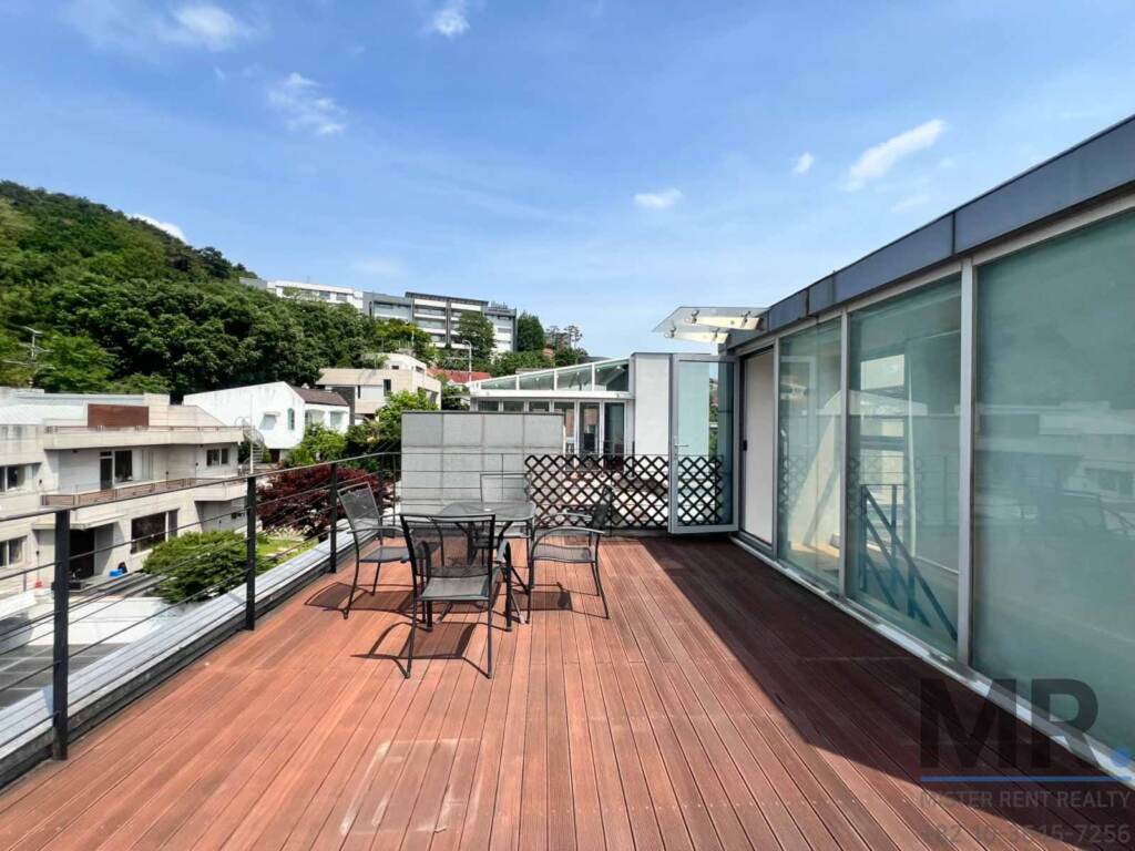Private rooftop terrace with wooden deck, outdoor table and hillside view