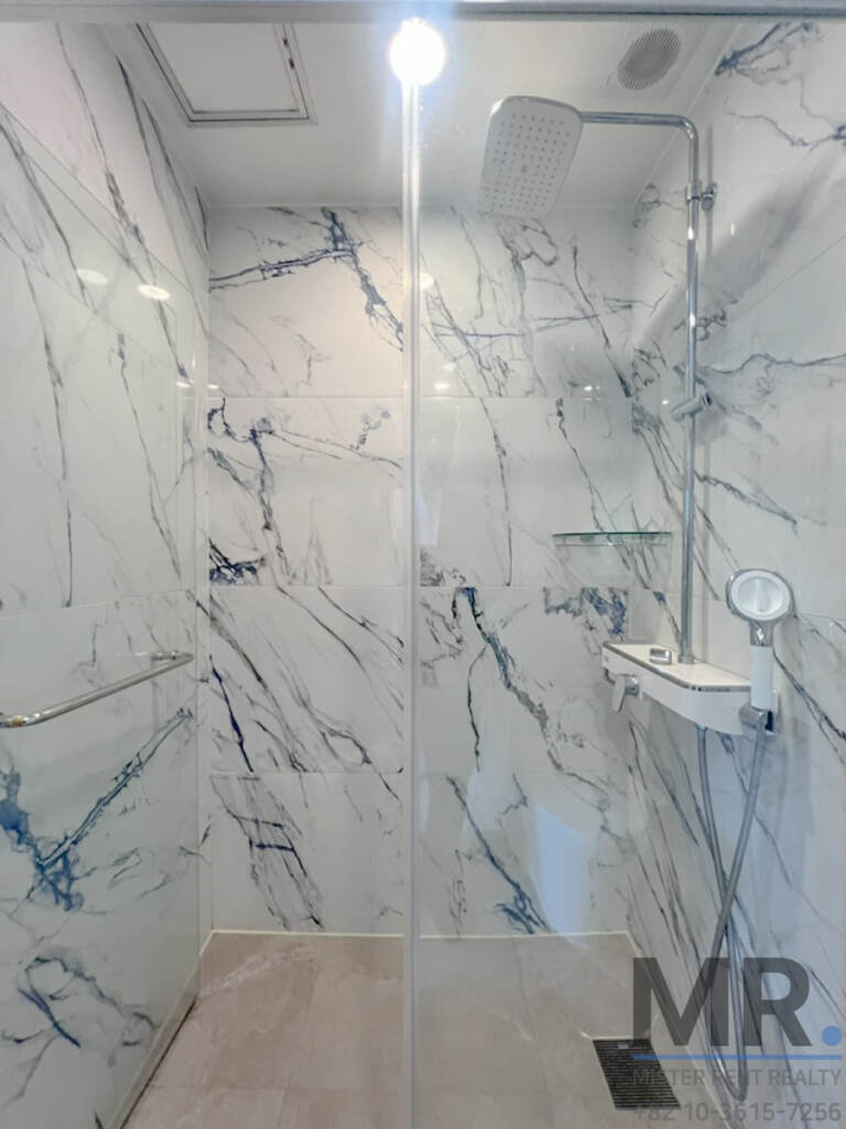 Walk-in shower with blue-veined marble tiles and rain shower