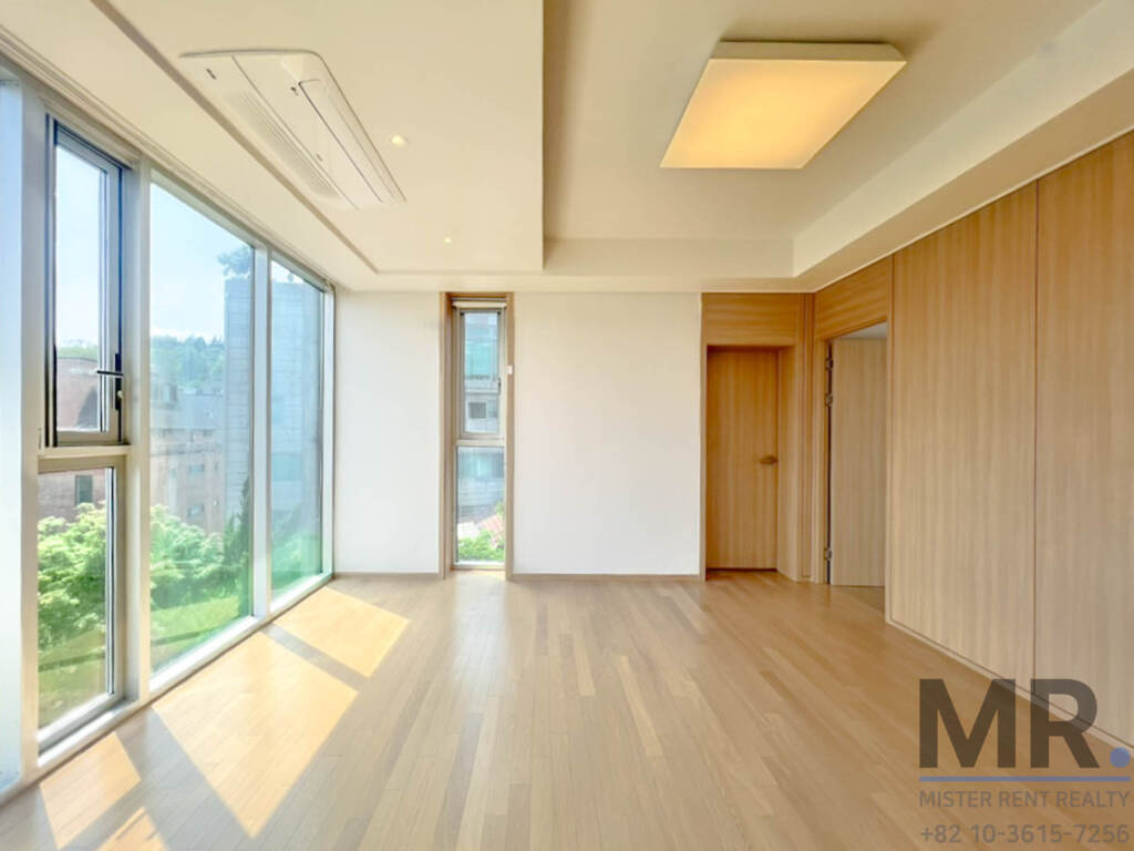 Corner living room with full-height windows and wood-paneled wall