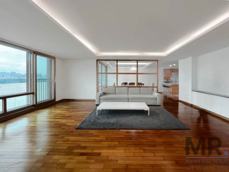 Living room with grey sofa, cove lighting and glass partition to the dining area