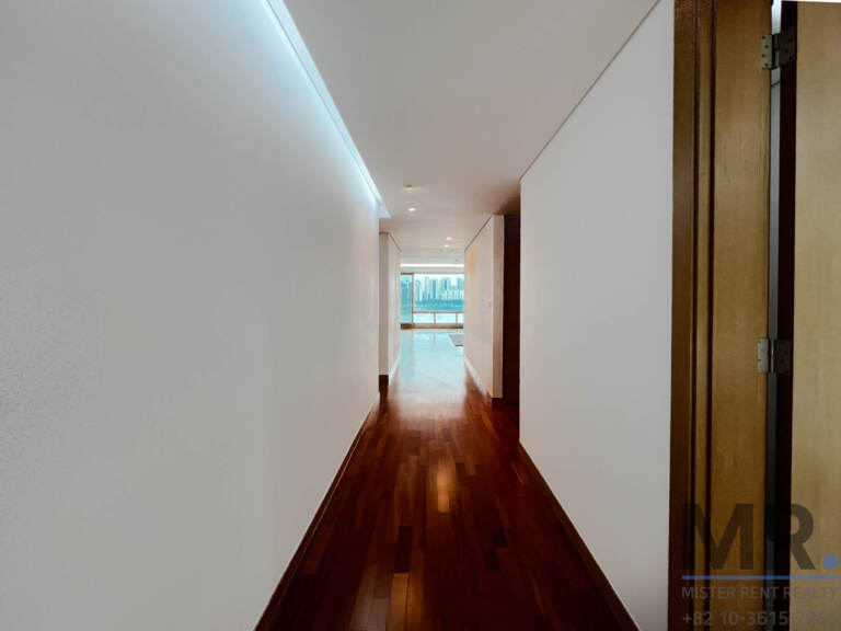 Long hallway with dark hardwood floor and window at the end