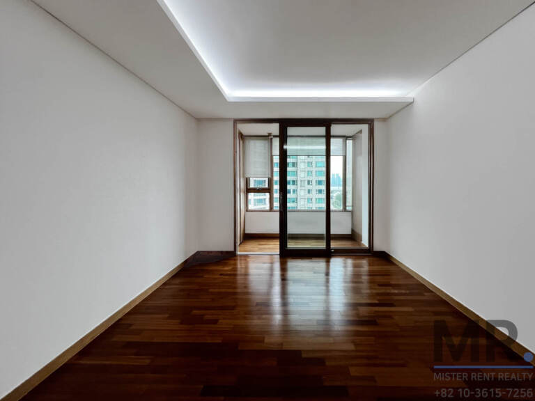 Narrow bedroom with dark wood floor and balcony door