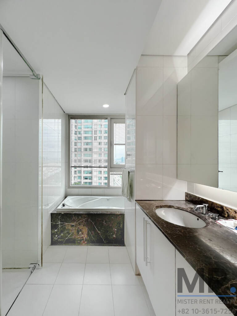 Master bathroom with long vanity and window above the bathtub