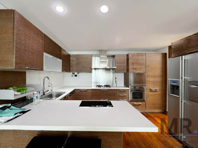 Kitchen with wood cabinets, white island and built-in oven