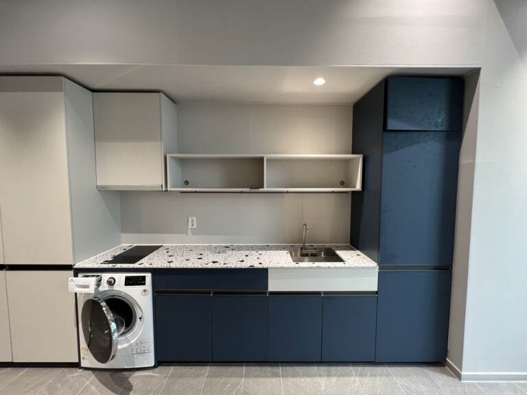 Compact kitchen with terrazzo counter, washing machine and blue cabinets