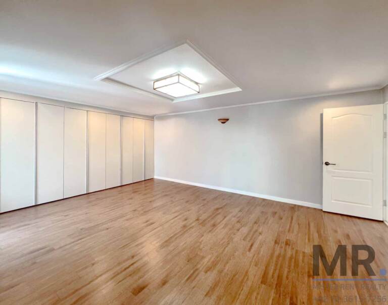 Spacious bedroom with white sliding wardrobes and coffered ceiling light