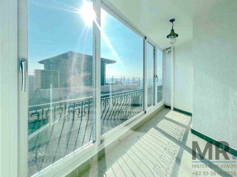 Enclosed sunroom balcony with sliding windows and wrought-iron railing