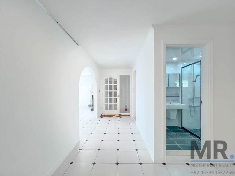 Hallway with arched opening leading to a bathroom with glass shower