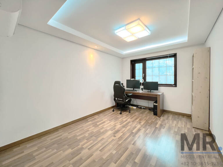 Home office bedroom with computer desk and tall wooden shelf