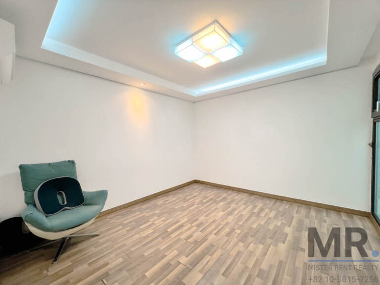 Bright bedroom with wood floor, ceiling cove light and a lounge chair