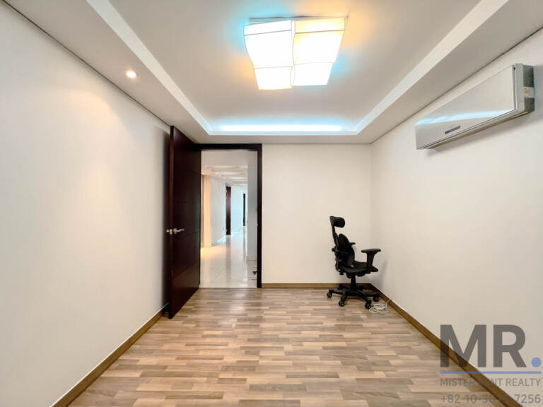 Bedroom with dark wood door, wall air conditioner and office chair