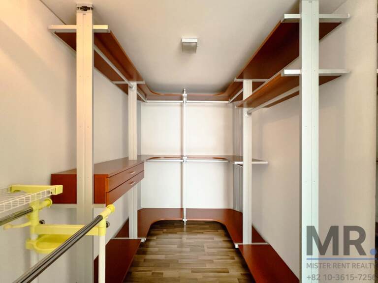 Walk-in closet with open wooden shelving and hanging rails