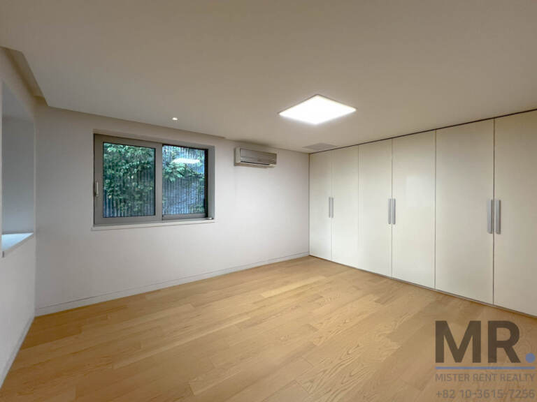 Bedroom with full-wall white wardrobe and window to greenery