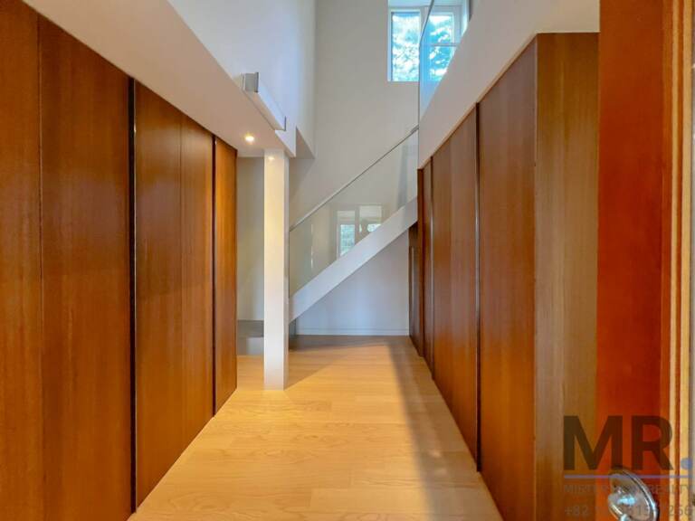 Entrance hall with wooden wall cabinets and glass staircase