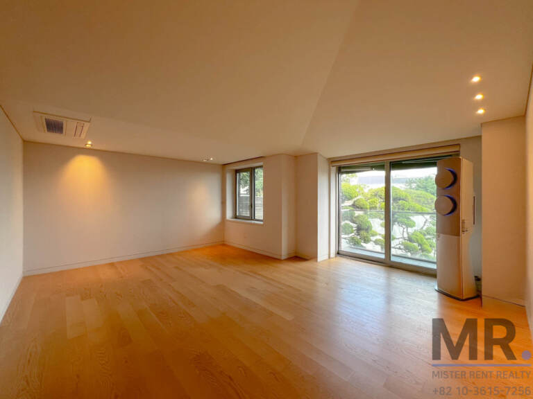 Spacious bedroom with sloped ceiling and sliding doors to a balcony with pine trees
