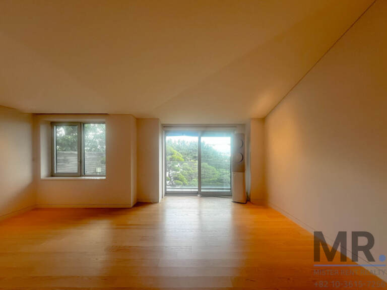 Large bedroom with oak floors, sloped ceiling and balcony door