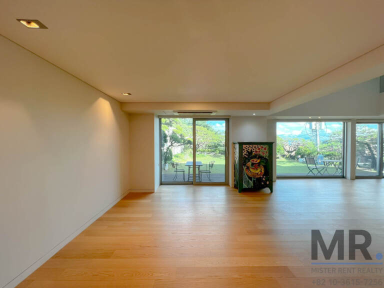 Open living area with oak floors and large windows facing the lawn