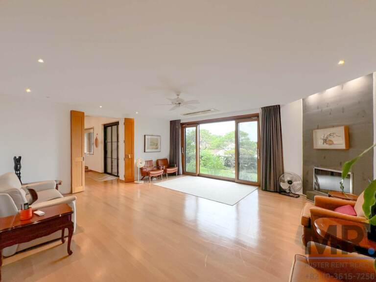 Open living space with ceiling fan, armchairs and garden-view doors