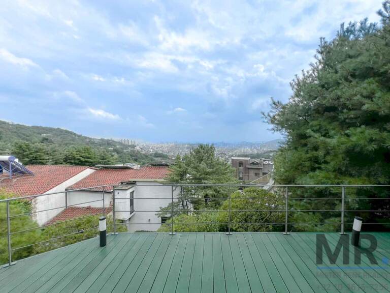 Green wooden deck with railing and mountain and city view