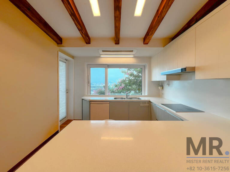 Kitchen with white cabinets, quartz counter and window facing the garden