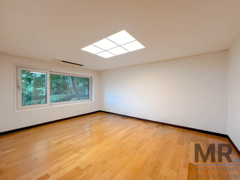Bedroom with hardwood floor and window looking onto greenery