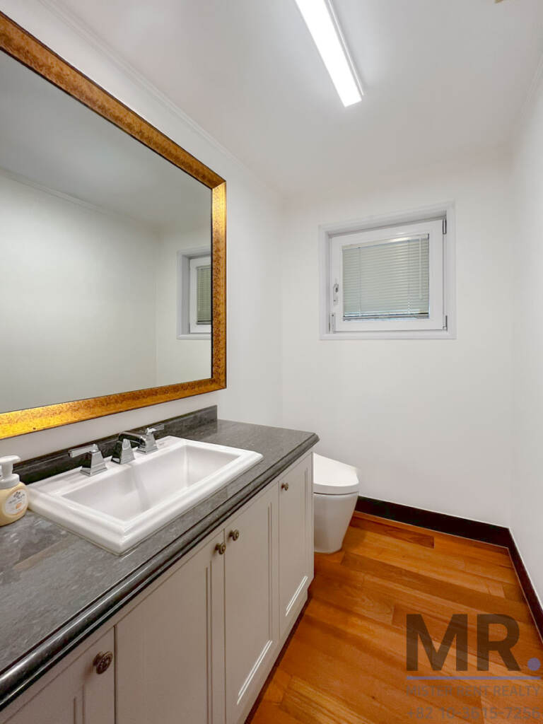 Powder room with gold-framed mirror, vanity sink and wooden floor