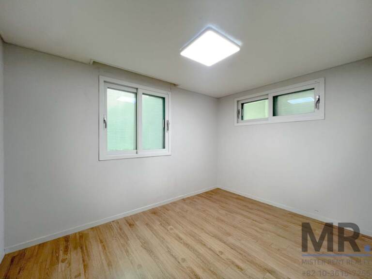 Bedroom with corner windows and light wood floor