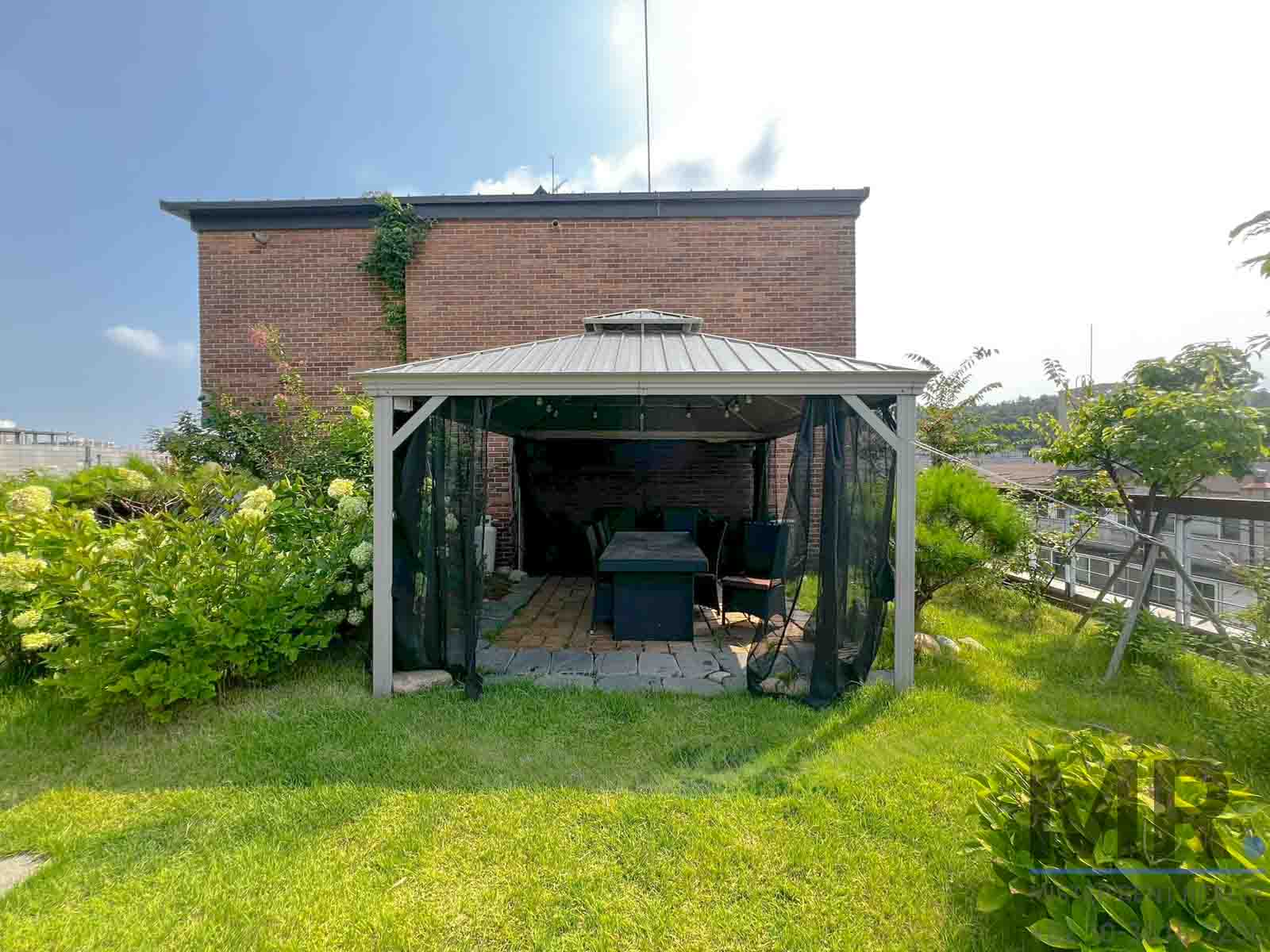 Cozy gazebo in lush garden setting.