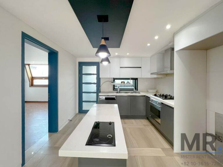 Galley kitchen with white island, induction cooktop and pendant lights