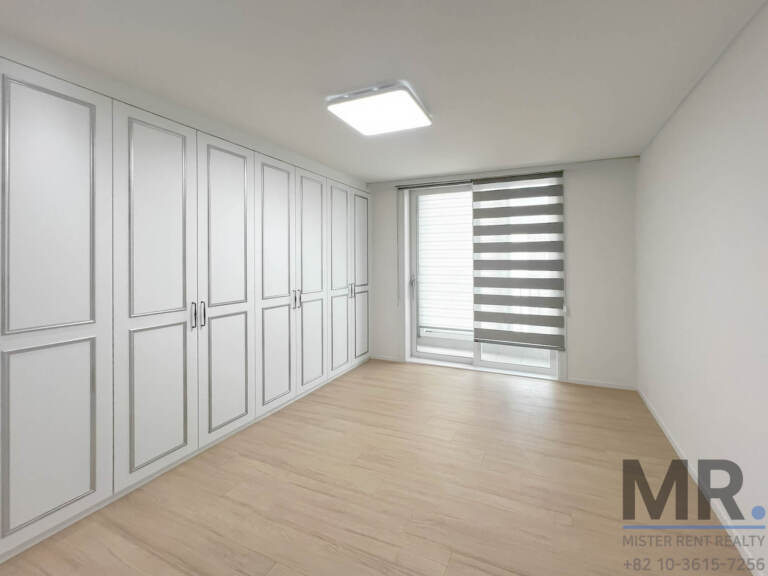 Master bedroom with full wall of paneled white wardrobes