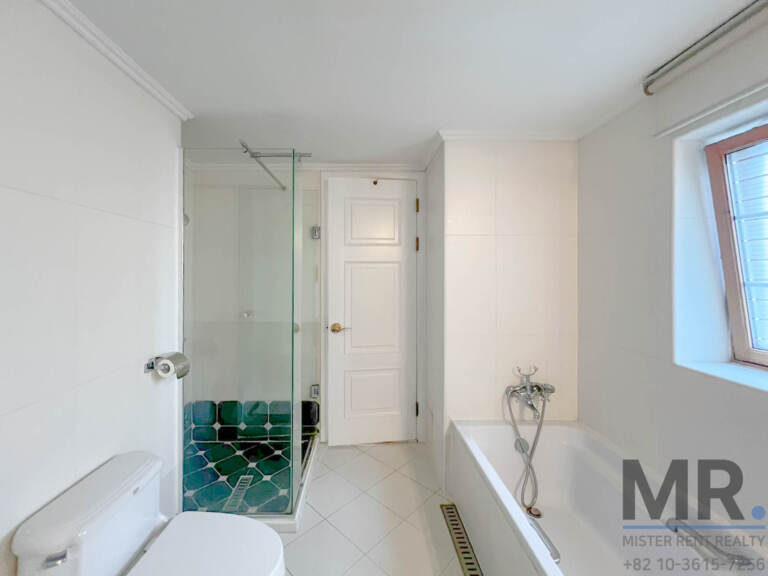 Bathroom with bathtub, glass shower and green mosaic tiles