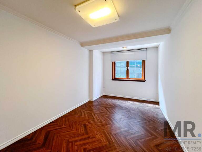 Narrow bedroom with window blind and parquet floor