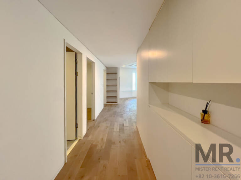 Hallway with built-in white storage and wood floor