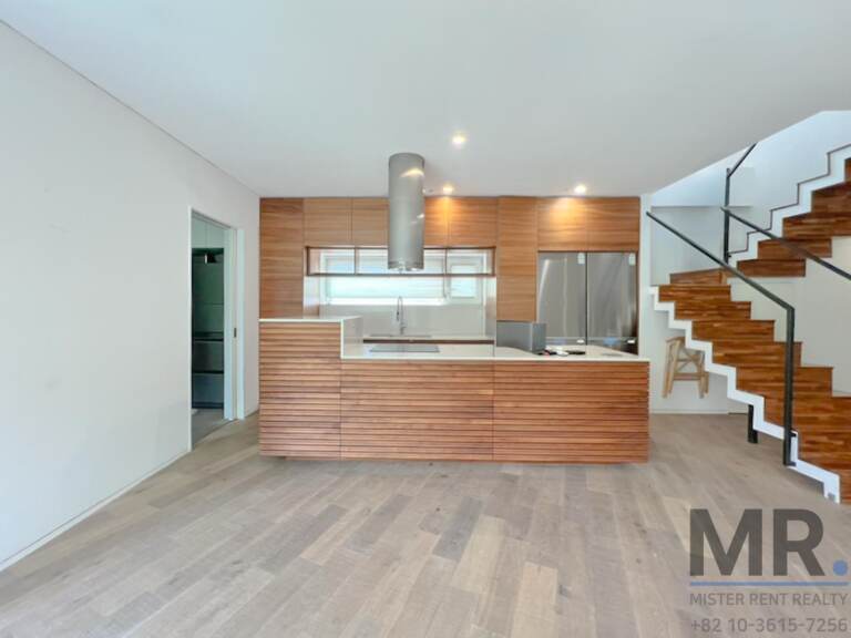 Kitchen with wood-slat island, stainless hood and stairs to the upper floor