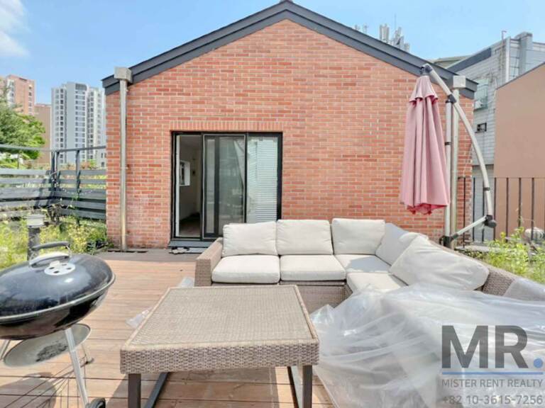 Rooftop deck with outdoor sofa, grill and red-brick wall