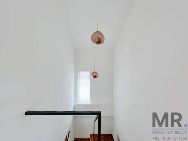Stairwell with copper pendant lights and black railing