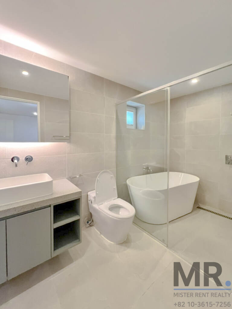 Bathroom with freestanding tub behind glass and wall-mounted vanity