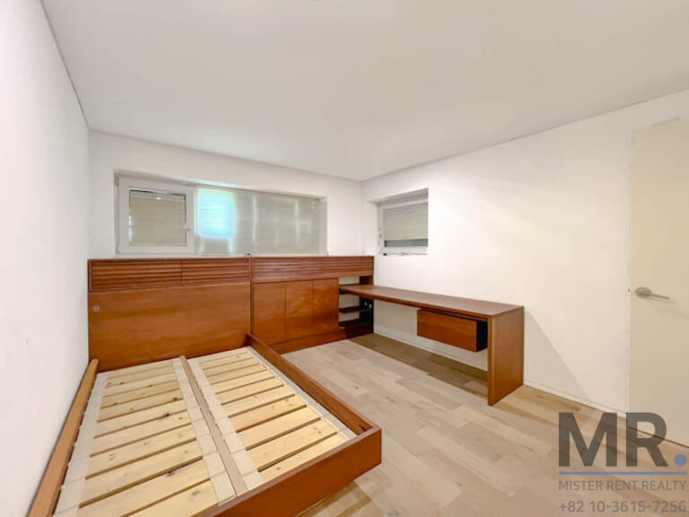 Bedroom with wooden bed frame, built-in desk and window