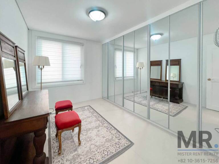 Bedroom with mirrored closet doors, antique vanity and floor lamp