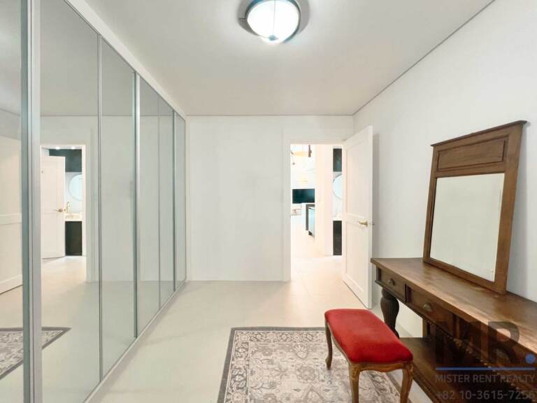 Dressing room with mirrored wardrobes, wooden vanity and red stool