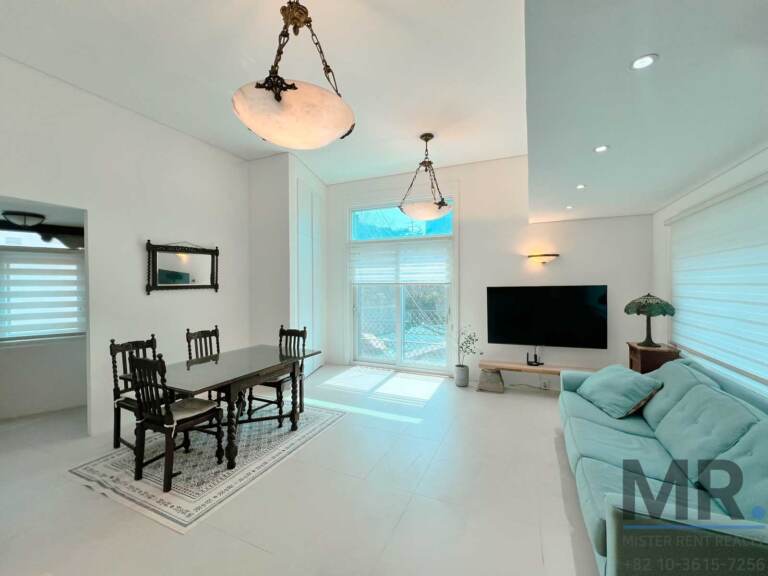 Dining area with carved wooden table, alabaster pendant lights and rug