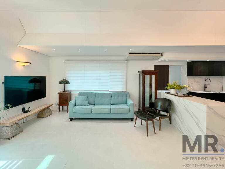 Living room with TV wall, teal sofa and marble kitchen counter