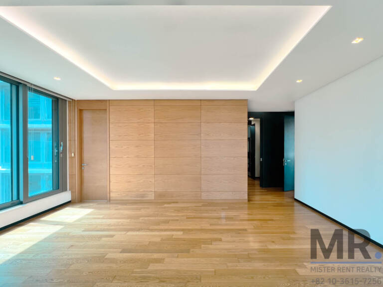 Master bedroom with wood-panel wall, tray ceiling and sunny window
