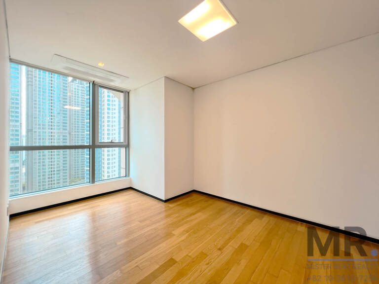 Bedroom with ceiling light and large window overlooking high-rises