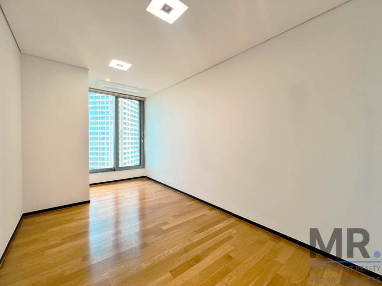 Bedroom with oak floor and window facing apartment towers