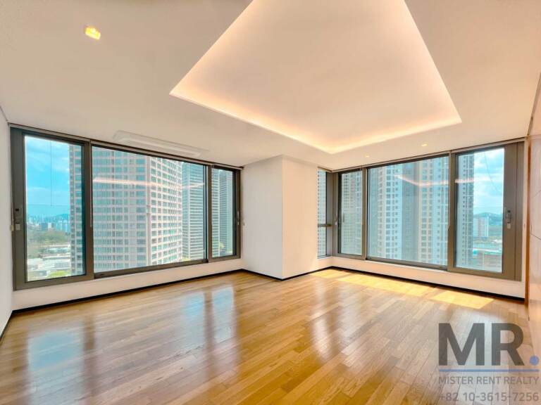 Empty corner room with tray ceiling lighting and windows on two sides