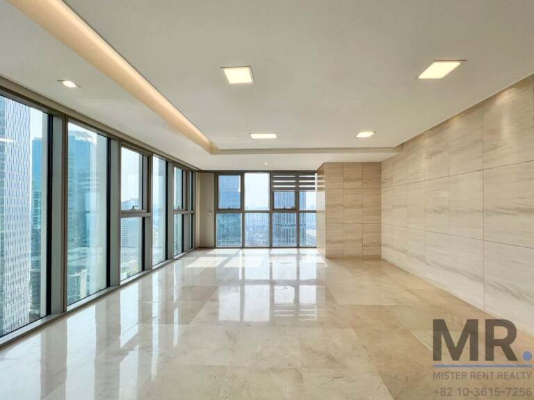 Spacious living room corner with tall windows and beige stone walls