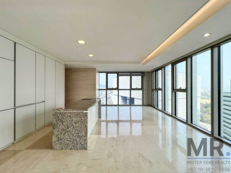Open kitchen with tall white cabinets, granite island and corner windows